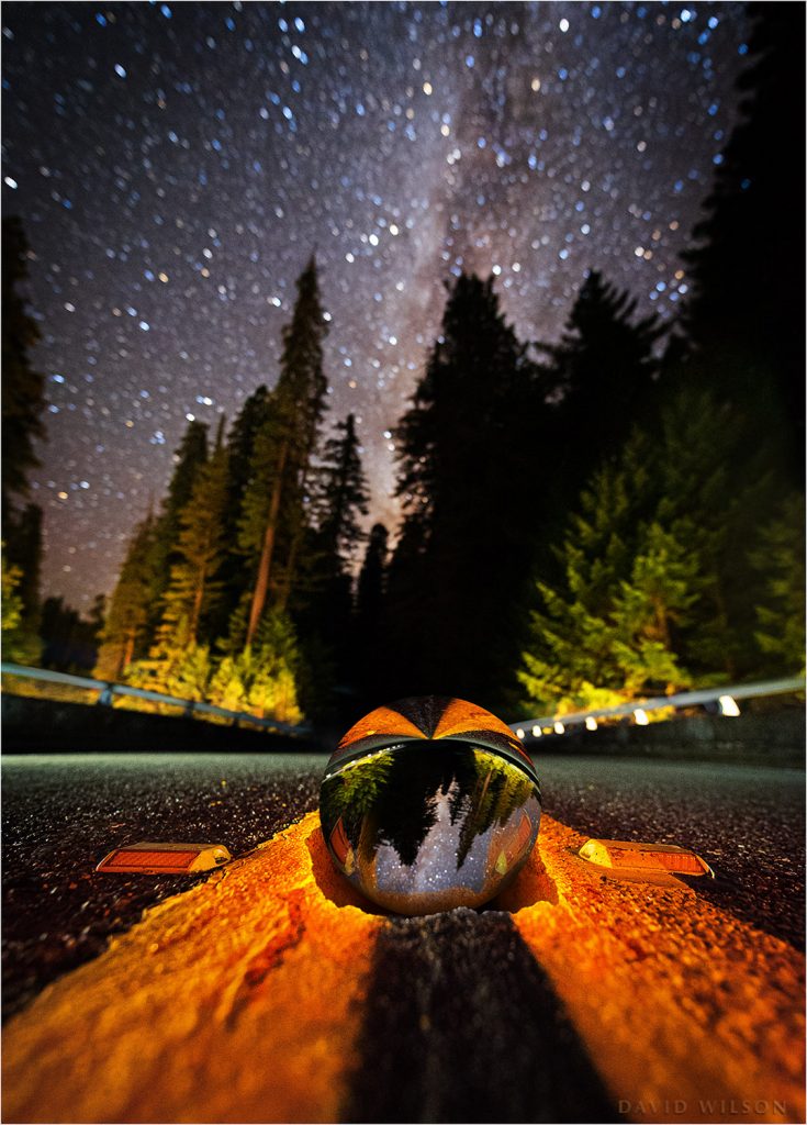 An apparent crystal ball and hole in a road beneath the Milky Way