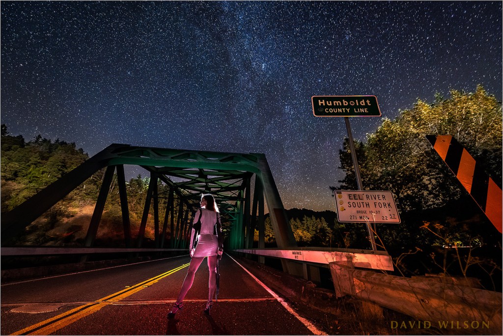 in color: Woman with shotgun on the Cooks Valley Bridge at the Humboldt County Line